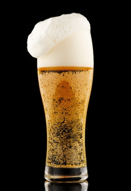 Light yellow beer with foam in a glass black background