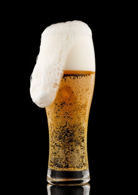 Light yellow beer with foam in a glass black background