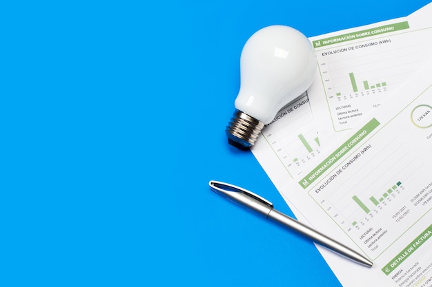 Photo a lightbulb and an electricity bill on a blue background