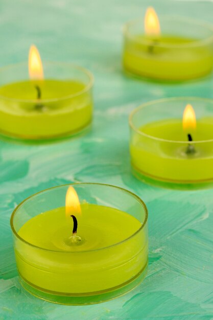 Lighted candles with beads on green background