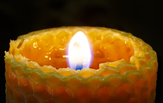 Lighted honeycomb candle on dark background.