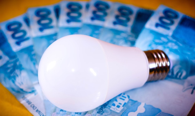 Foto lampada led a diodi emettitori di luce su diverse fatture in denaro reale brasiliano concetto di prezzo dell'elettricità