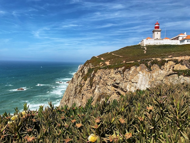 Photo lighthouse amidst sea and buildings against sky