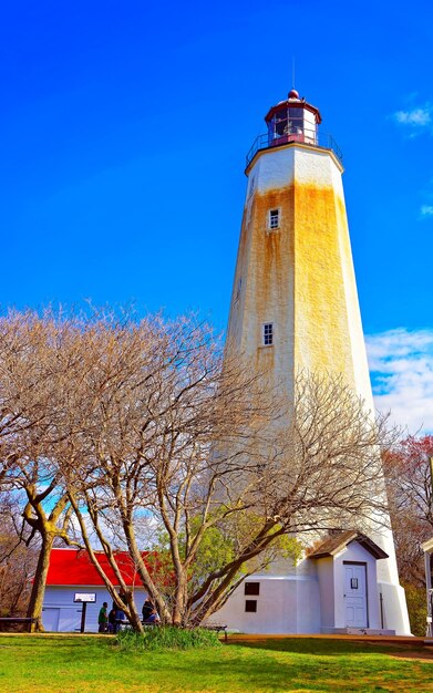 Lighthouse at atlantic ocean bay shore at sandy hook. light\
house tower is called us navesink twin lights. it is in highlands\
in monmouth county in new jersey, usa. blue sky background