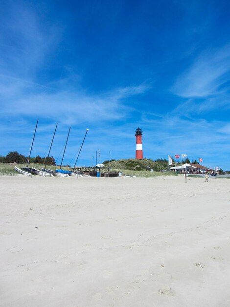 Photo lighthouse on beach against blue sky