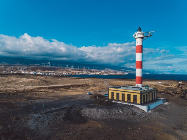 Lighthouse on beach by buildings against sky