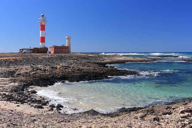 Foto faro sulla spiaggia sul mare contro un cielo limpido