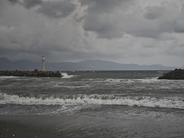 Lighthouse on beach by sea against sky