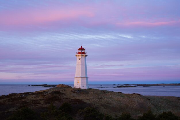 Lighthouse on beach by sea against sky