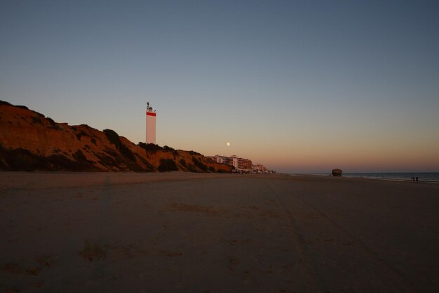 Photo a lighthouse at the beach on sunset