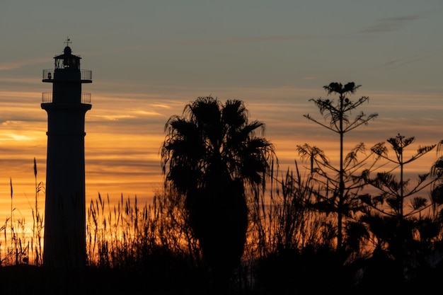 Foto faro sulla spiaggia al tramonto