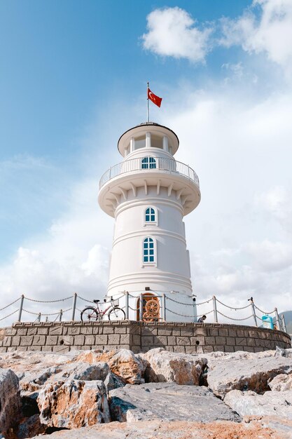 A lighthouse on a beach with a flag on the top