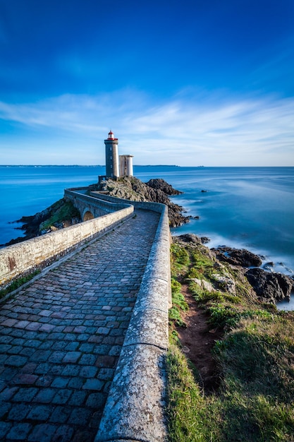 Lighthouse by sea against blue sky