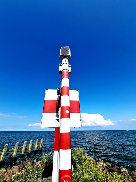 Lighthouse by sea against blue sky