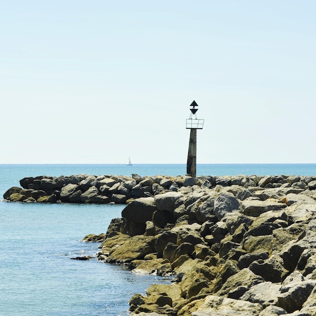 Lighthouse by sea against clear sky