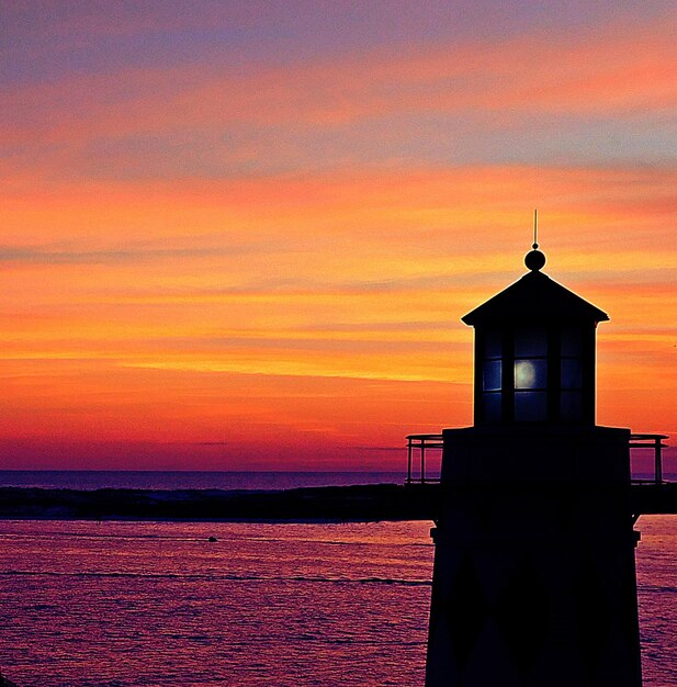 Photo lighthouse by sea against sky during sunset