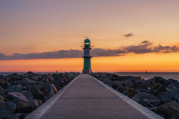 写真 夕暮れの空に照らされた海の灯台