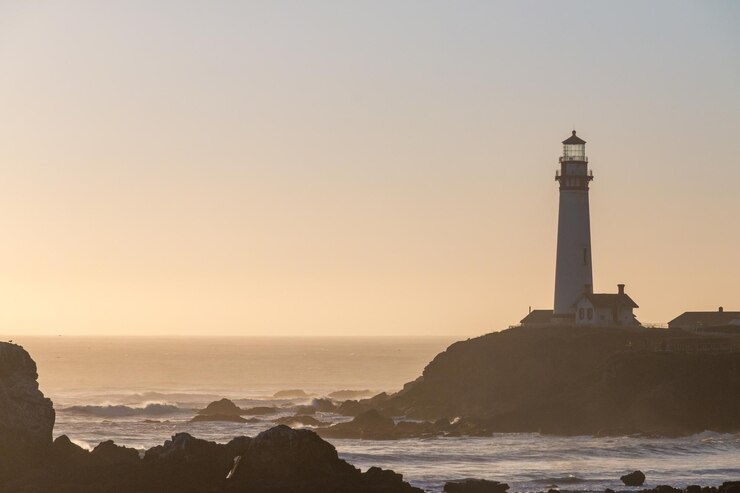 Photo lighthouse by sea against sky during sunset