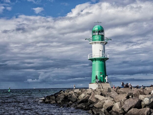 Lighthouse by sea against sky