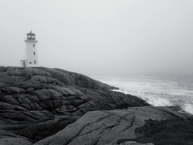 Photo lighthouse by sea against sky