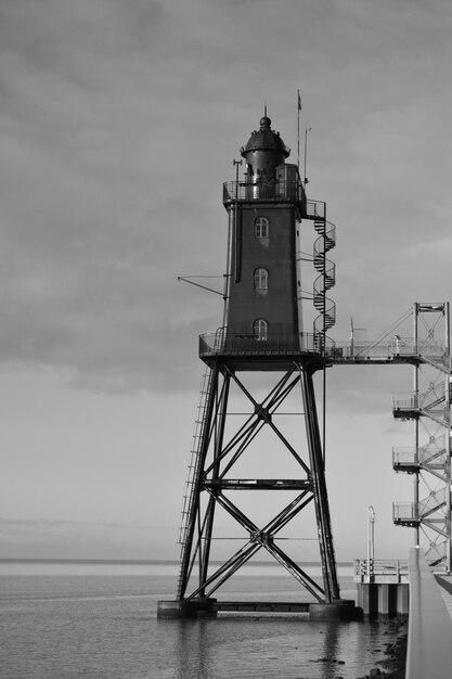 Photo lighthouse by sea against sky