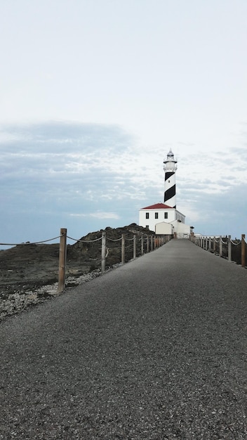 Lighthouse by sea against sky