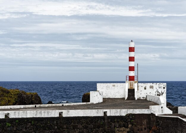 Lighthouse by sea against sky