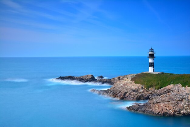 Lighthouse by sea against sky