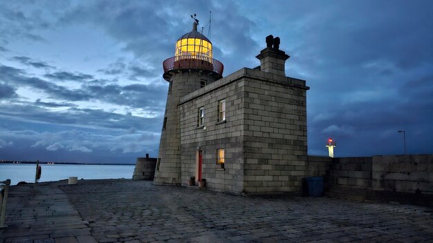 Lighthouse by sea against sky