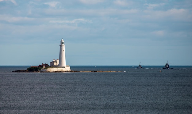 Photo lighthouse by sea against sky