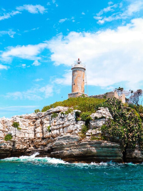 Lighthouse by sea against sky