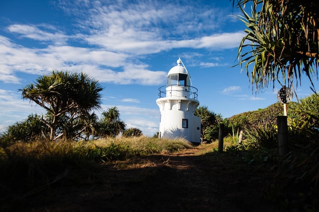 Lighthouse by trees on field against sky