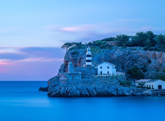 Photo lighthouse on cliff by sea at twilight