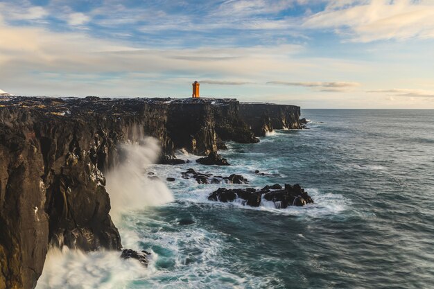 Lighthouse over the cliff, ocean seashore in Iceland