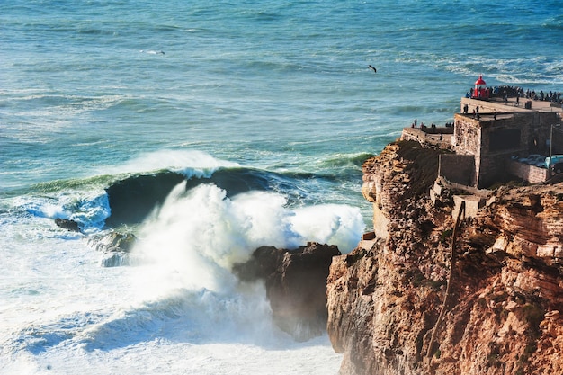 Faro sulla costa dell'oceano atlantico a nazare, portogallo. in questo luogo le onde più grandi del mondo a causa del canyon sottomarino