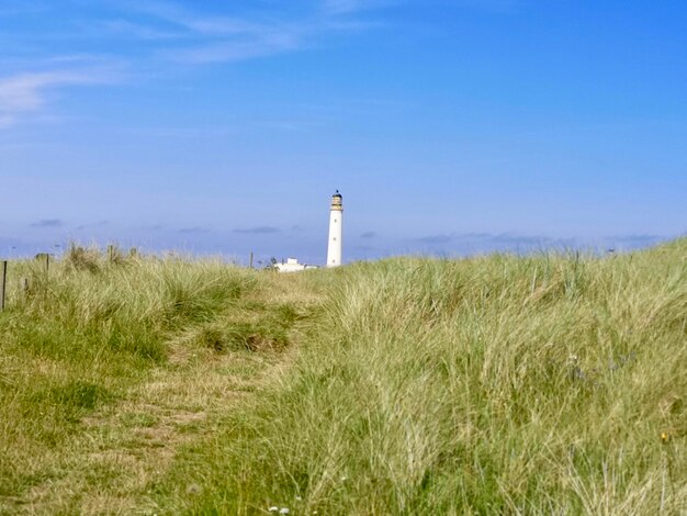 Photo lighthouse on field against sky