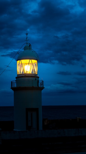 スペインの海岸の暗い夜に輝く灯台