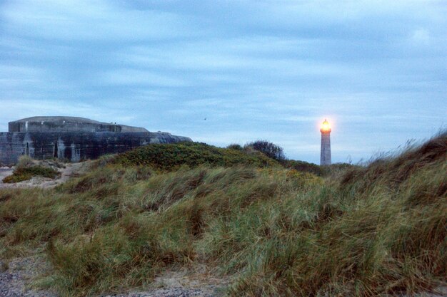 Photo lighthouse on grassy beach against the sky