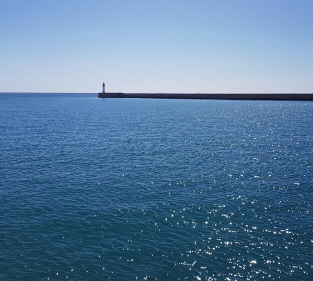 石の道と青い空で海で隔離する灯台