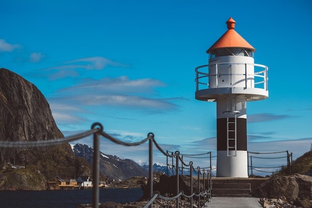 Lighthouse on the pier on the background of the mountains and the blue sky on the Lofoten Islands