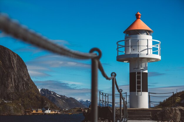 Lighthouse on the pier on the background of the mountains and the blue sky on the Lofoten Islands.