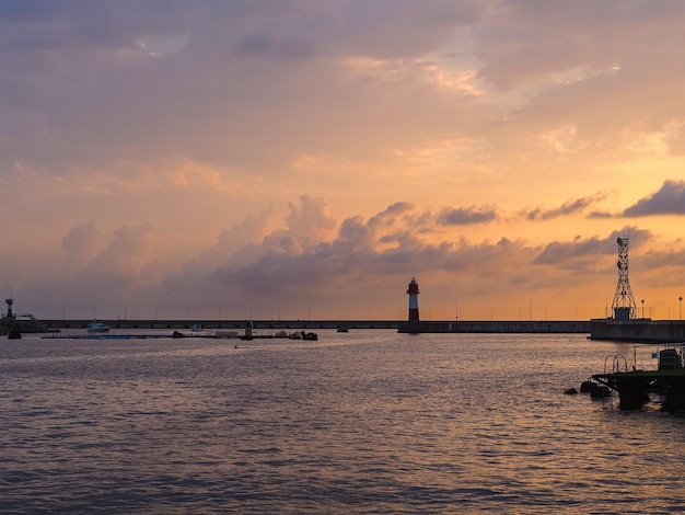 Lighthouse in the port against the backdrop of the sunset sky