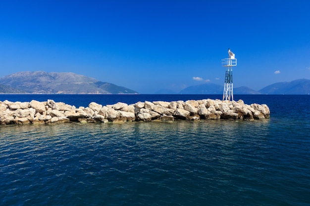 Lighthouse on rock by sea against blue sky