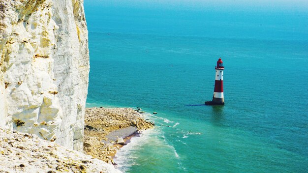 Photo lighthouse on rock by sea