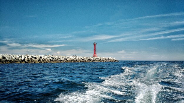 Lighthouse in sea against blue sky