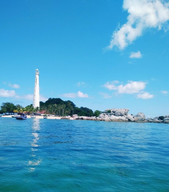 Lighthouse in sea against sky