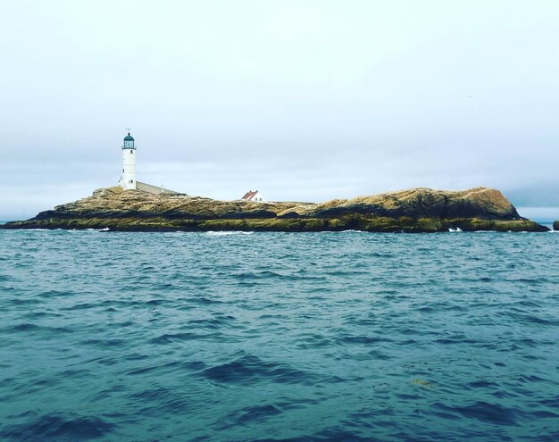 Photo lighthouse in sea against sky