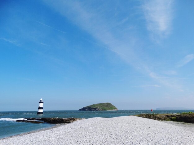 Lighthouse in sea against sky