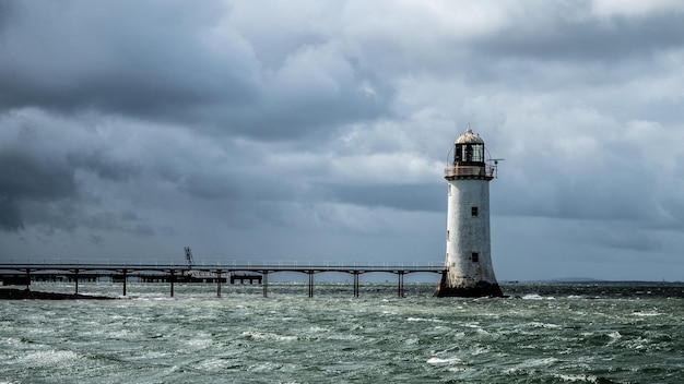 Photo lighthouse in sea against sky