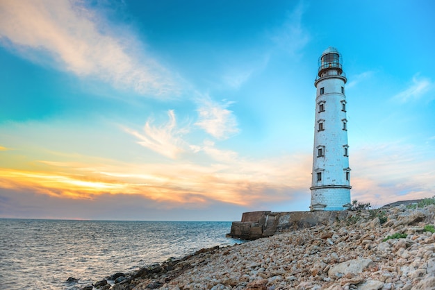 Foto faro sulla costa del mare con cielo al tramonto